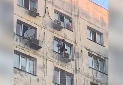 Девојче виси на прозорец на деветти кат на зграда, соседите во паника (Вознемирувачко видео) 
