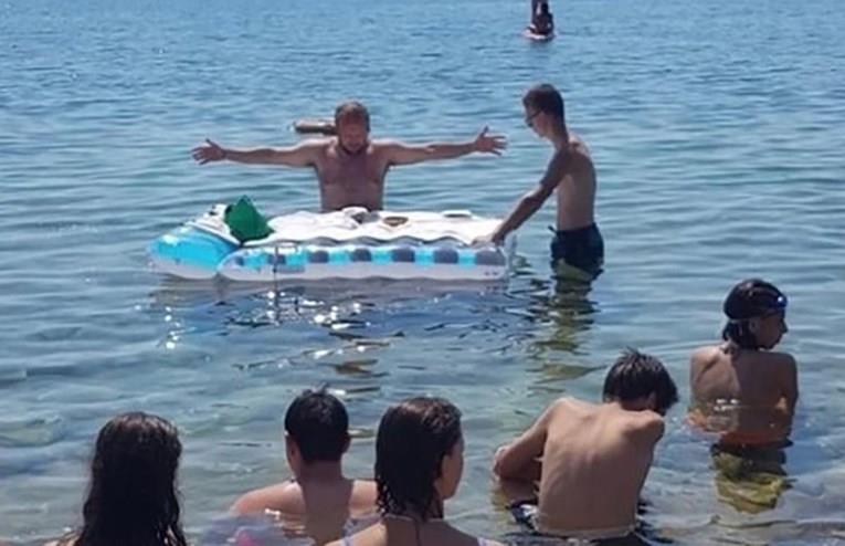 Му било жешко: Свештеник одржал миса во море, олтар му бил душекот за плажа (ВИДЕО)