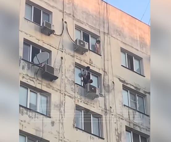 Девојче виси на прозорец на деветти кат на зграда, соседите во паника (Вознемирувачко видео) 
